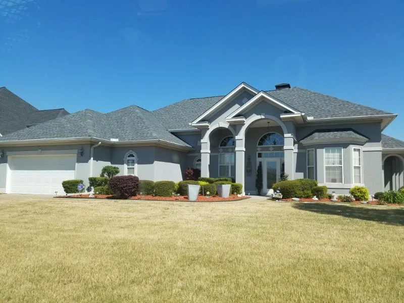 Light-colored home with an arched entrance and shingle roof from CAR’s residential portfolio